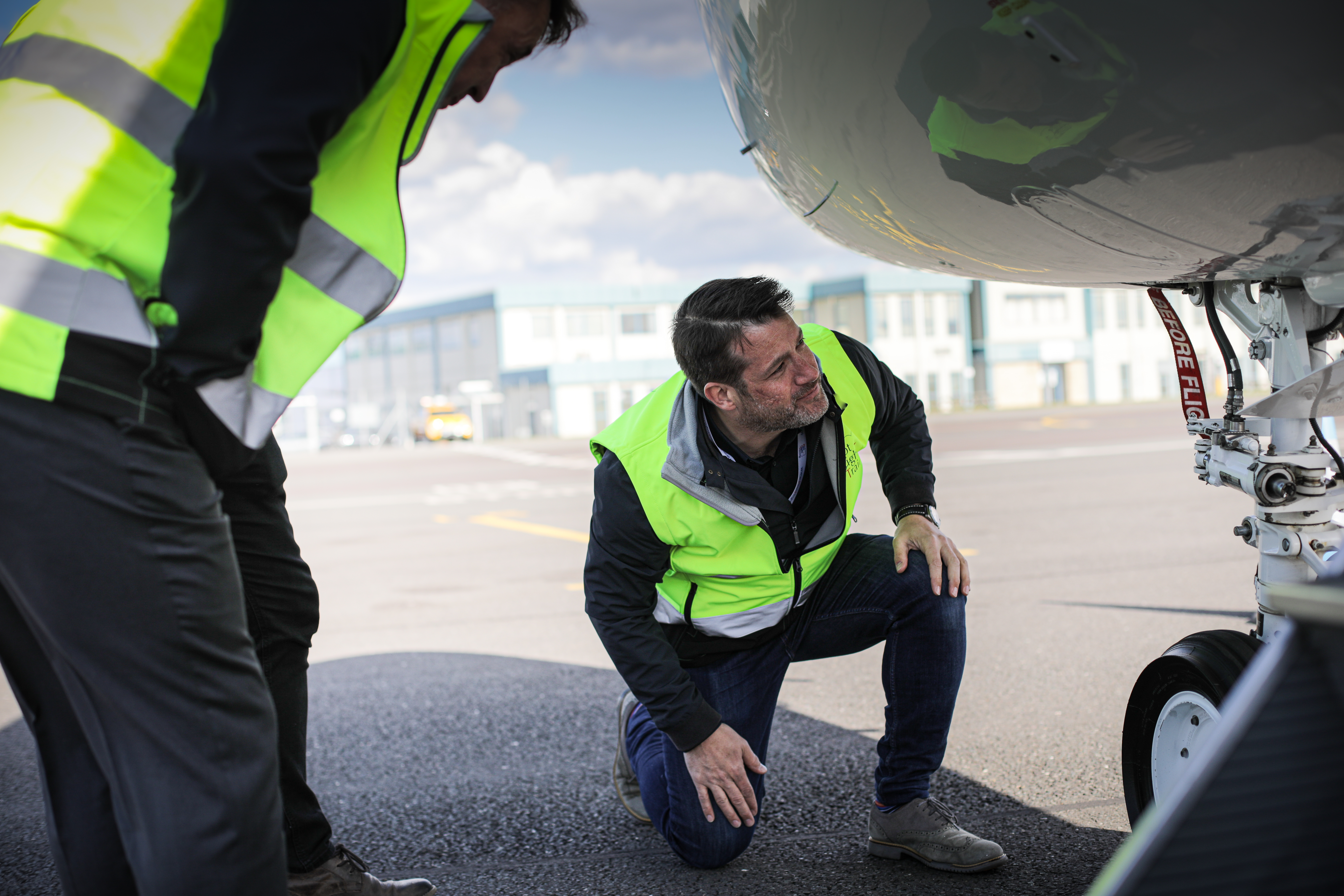 Two people in high-visibility clothing inspecting an aircraft exterior